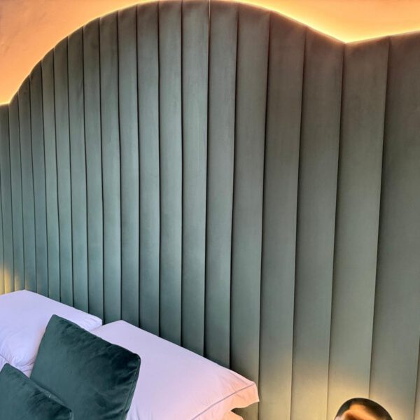 Bespoke green fluted upholstered headboard with warm bedroom lighting