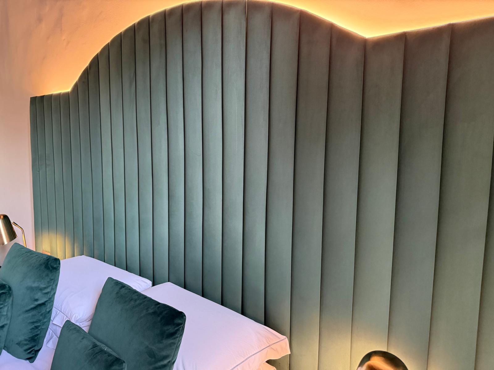 Bespoke green fluted upholstered headboard with warm bedroom lighting