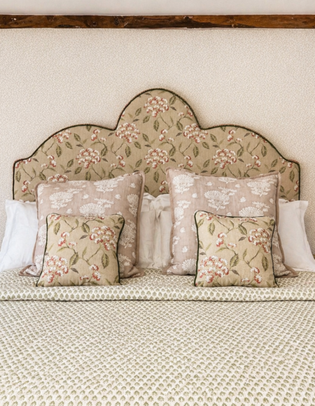 Bespoke floral upholstered headboard with matching cushions and contrast piping