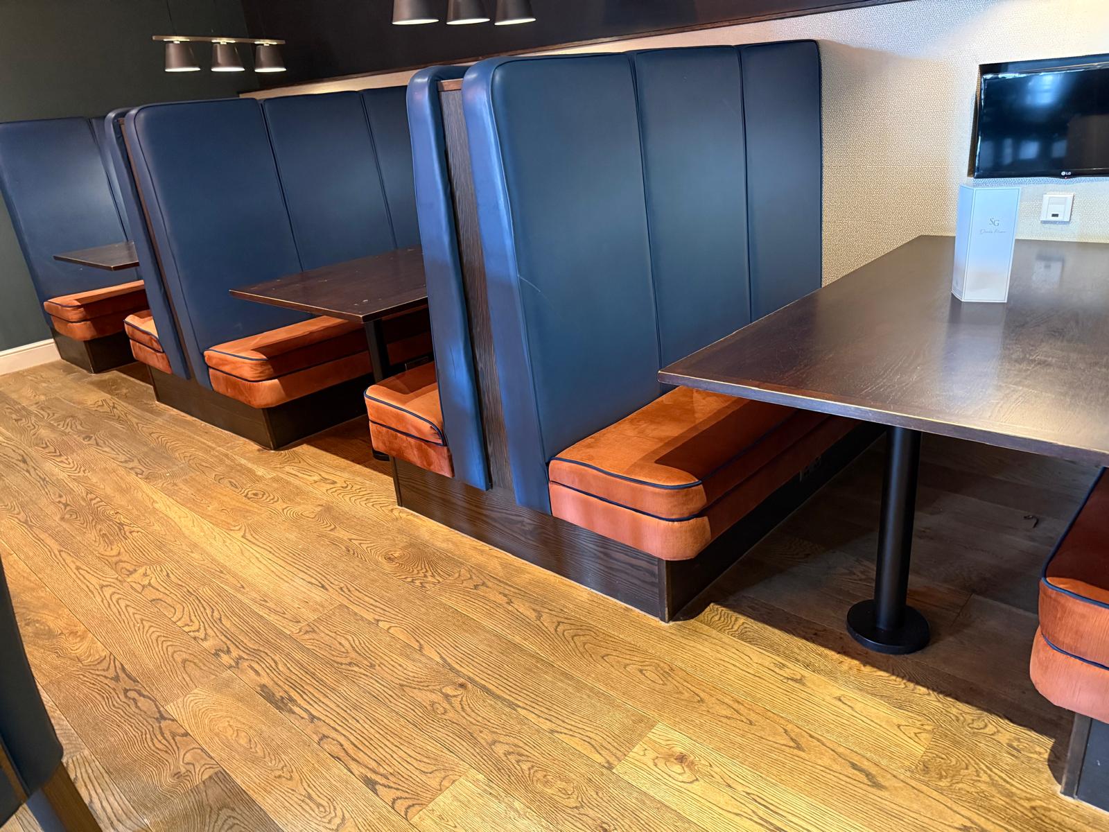 Commercial hotel bar booth seating reupholstery with burnt orange and navy blue banquette seating by Creature Comforts Upholstery