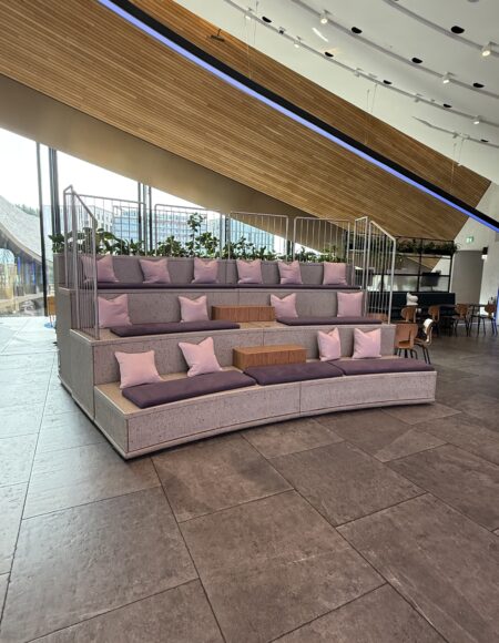 Commercial retail relaxation station with curved tiered upholstered seating and cushions in a modern shop interior.