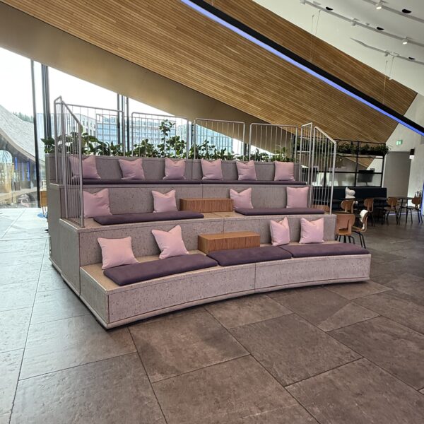 Commercial retail relaxation station with curved tiered upholstered seating and cushions in a modern shop interior.