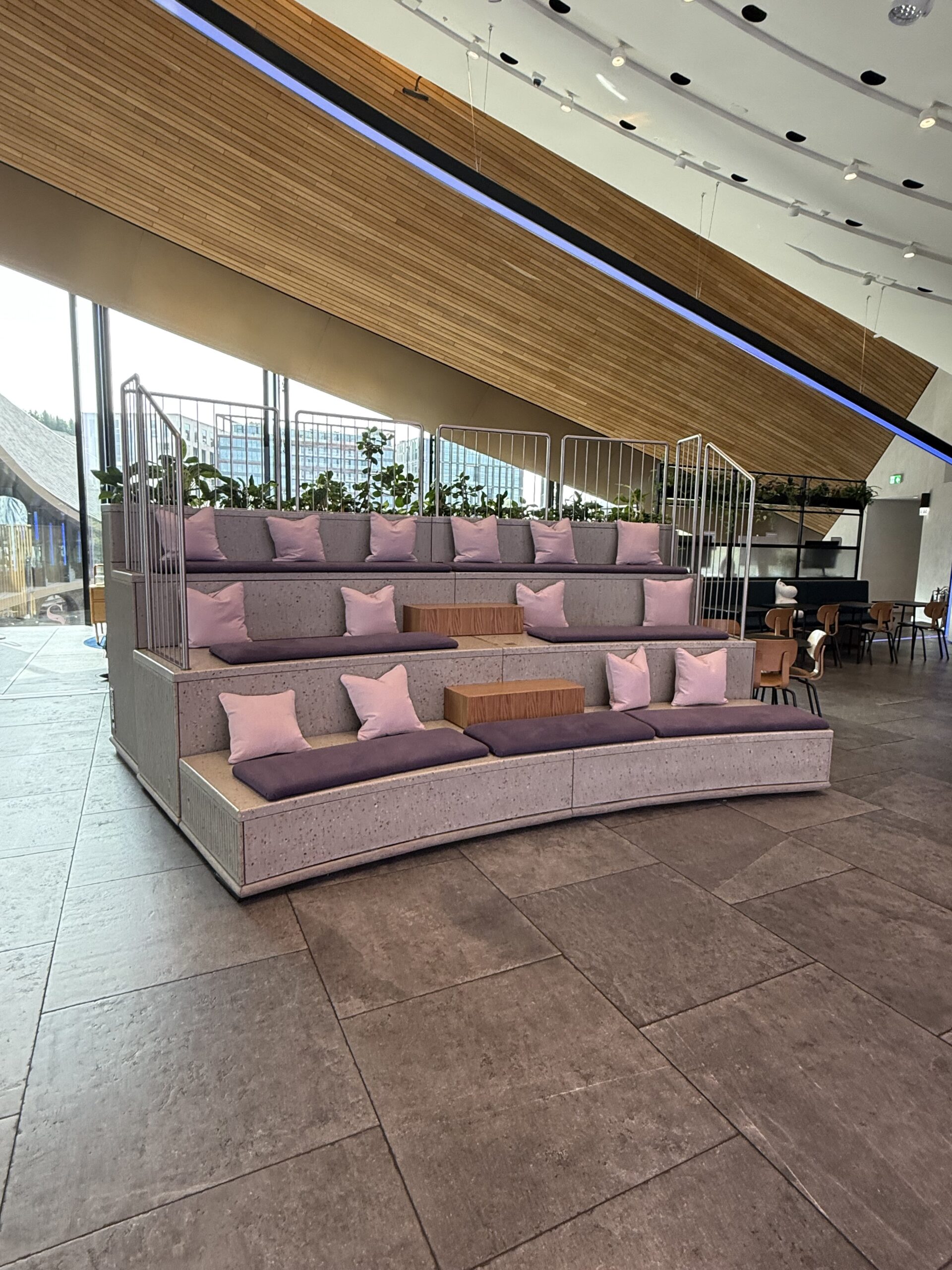 Commercial retail relaxation station with curved tiered upholstered seating and cushions in a modern shop interior.