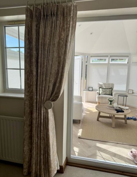 Bespoke handmade double pinch pleat curtains in textured neutral fabric with decorative tieback.