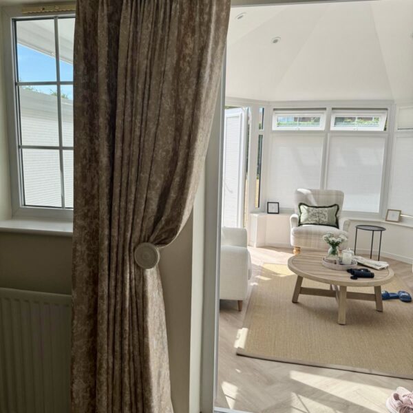 Bespoke handmade double pinch pleat curtains in textured neutral fabric with decorative tieback.