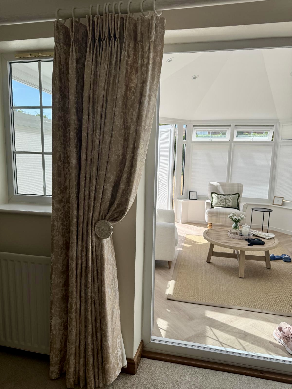 Bespoke handmade double pinch pleat curtains in textured neutral fabric with decorative tieback.